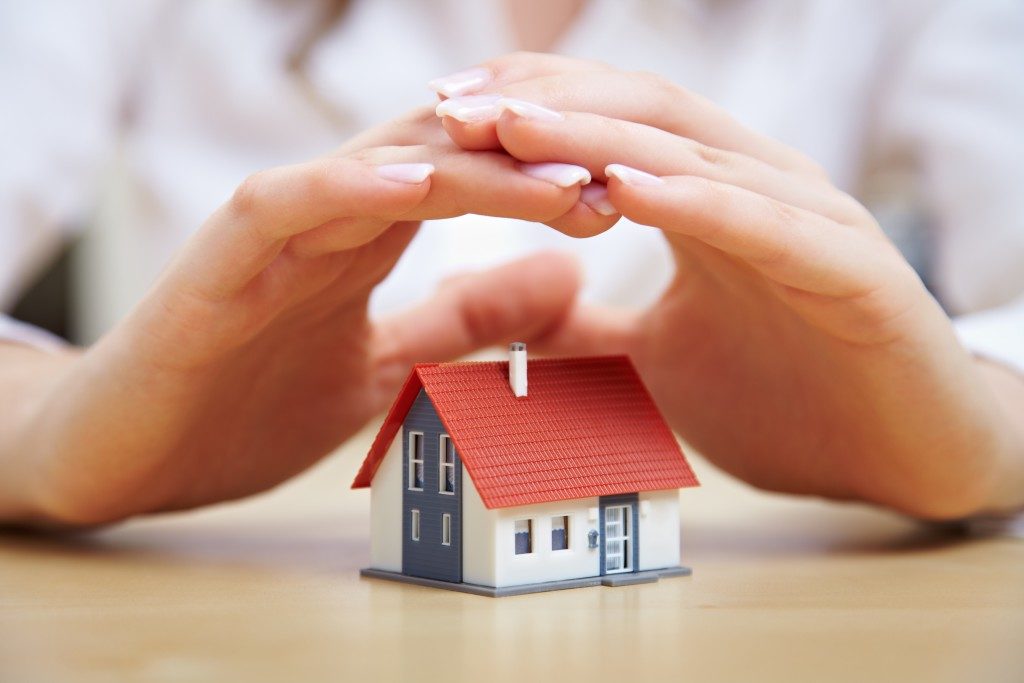 hands covering a miniature house